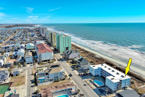An aerial view of a coastal town with buildings along the beach, a road, and a body of water. - Direct Oceanfront, Cherry Grove, Elevator, 2 Bedroom Condo (North Myrtle Beach)