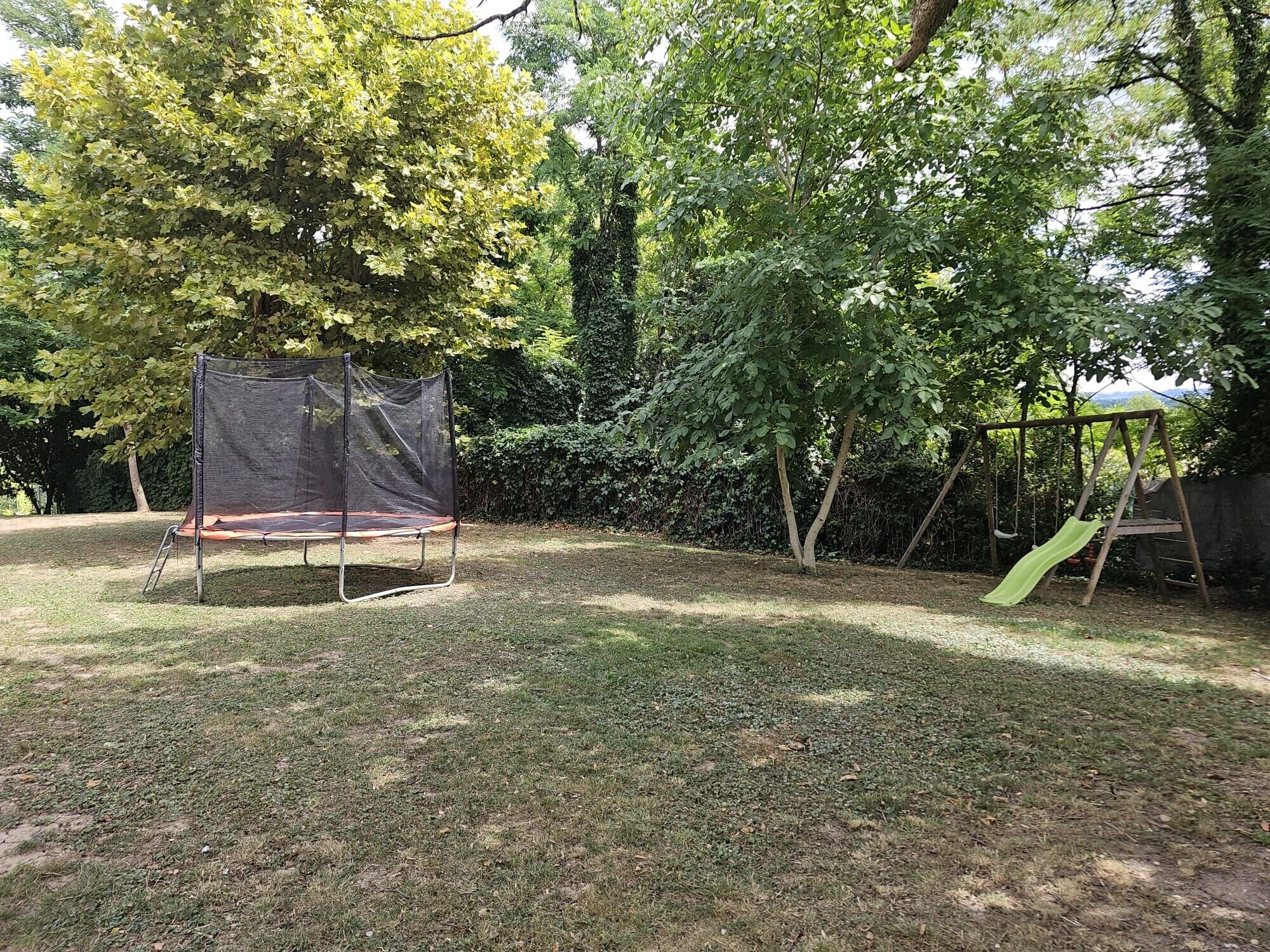 A backyard with a trampoline and a slide.