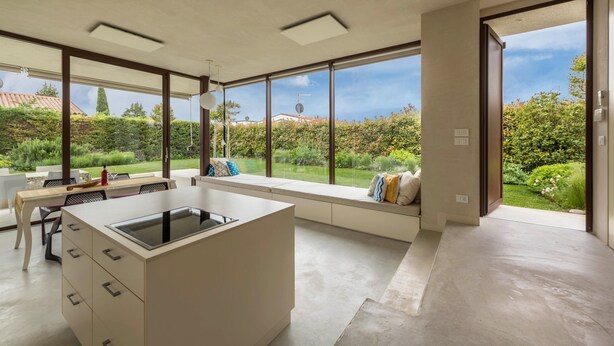 Une cuisine moderne dotée de grandes fenêtres, d’un coin repas et offrant une vue sur un jardin.