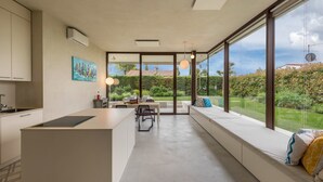 Une cuisine moderne avec un coin repas, de grandes fenêtres et une vue sur la verdure.