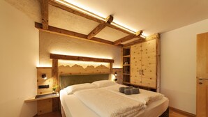 Une chambre à coucher comprenant un lit, une tête de lit en bois, des tables de chevet et une armoire.