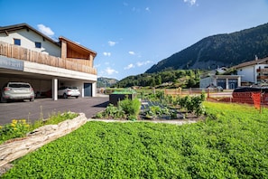 Un immeuble doté d’un balcon, d’un espace de stationnement et d’un jardin planté.