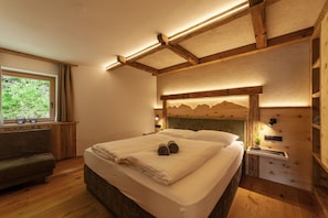 Une chambre à coucher avec une tête de lit en bois, un lit sur lequel sont pliées des serviettes, une table de chevet et une fenêtre avec des rideaux.
