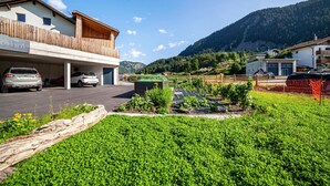Ein Gebäude mit Balkon, Parkplatz und einem Garten mit Pflanzen.