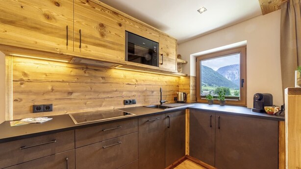 Eine moderne Küche mit Holzausstattung, integriertem Backofen und Fenster mit Blick auf die Berge.