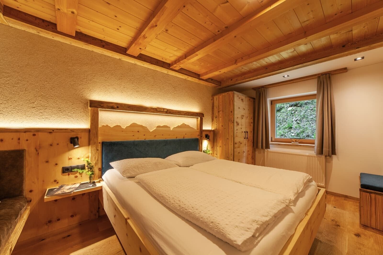 Quarto de cabana de madeira com cama, mesa de cabeceira, janela com cortinas e teto de madeira.