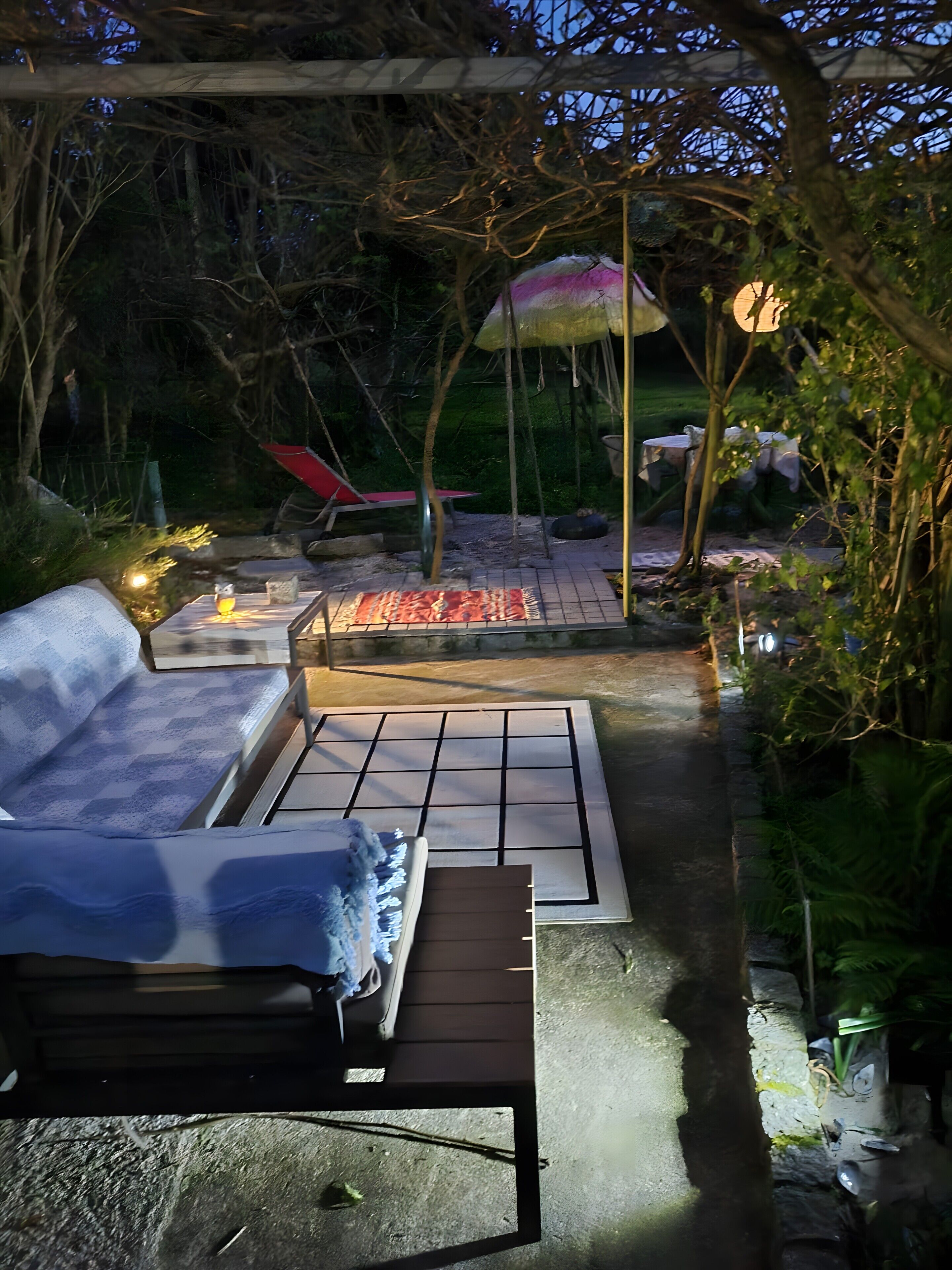 An outdoor patio area with a seating arrangement, a fire pit, and a pergola structure.