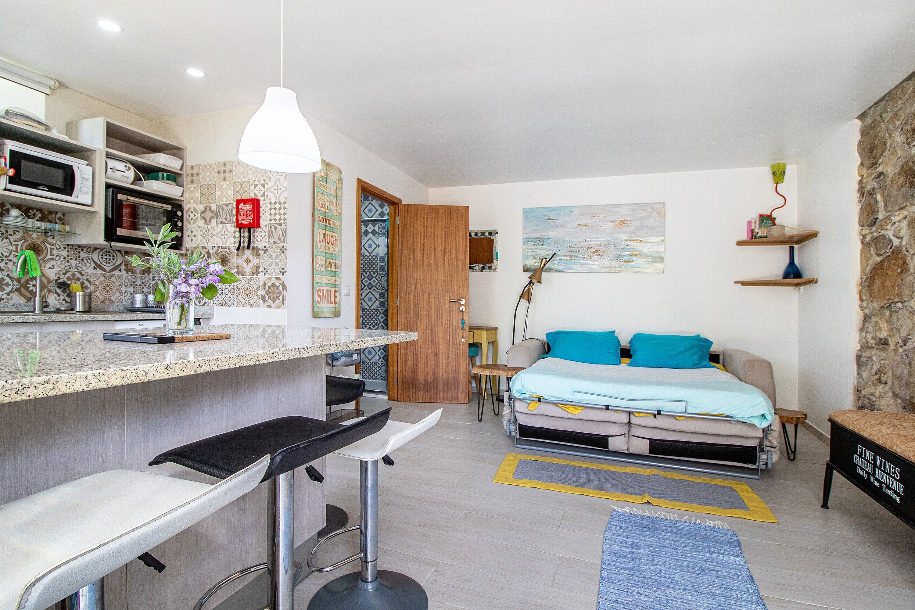 A compact living space with a kitchenette, a bed, a dining area, and a small seating area.