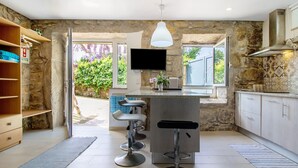 Cozinha moderna com paredes de pedra, um espaço bar e uma televisão.