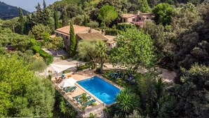 Uma villa com piscina, rodeada por vegetação exuberante e colinas.