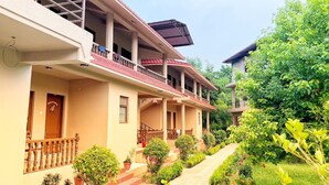 A multi-story building with balconies and a garden pathway. - Safari Club (Sauraha)