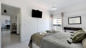 Een slaapkamer met een bed, een televisie, een raam en uitzicht op het omliggende landschap.