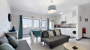 Een moderne woonkamer met een bank, een ronde tafel en een eethoek met een tafel en stoelen.