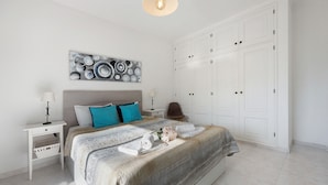 A bedroom with a bed, nightstands, a dresser, and a wall art piece. - Apartment "Refúgio Praia da Rocha" with Sea View, Balcony & Wi-Fi (Portimão)