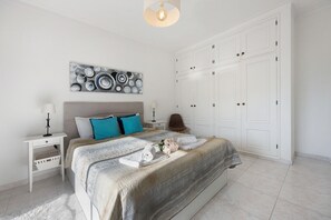 Une chambre à coucher comprenant un lit, des tables de chevet, une commode et une œuvre d’art murale.
