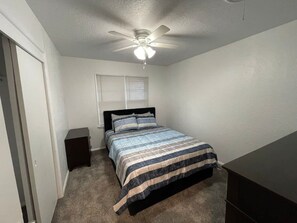 A bedroom with a bed, a nightstand, a ceiling fan, and a window with blinds. - Spacious 3-Bedroom Home Convenient to Fort Sill (Lawton)