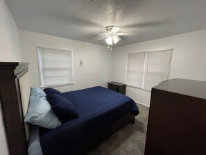 A bedroom with a bed, two nightstands, a dresser, and a ceiling fan.