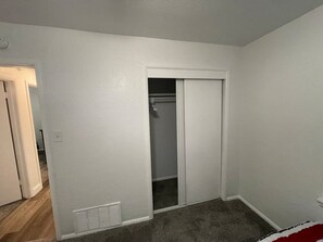 A room with a white door leading to a closet, a vent on the floor, and a carpeted floor. - Spacious 3-Bedroom Home Convenient to Fort Sill (Lawton)