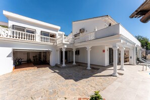 A courtyard with a stone floor, white buildings with balconies, and a covered area with columns. - Holiday Home 'Beachfront Luxury Villa La Cala' with Private Pool, Wi-Fi and Air Conditioning (Las Lagunas de Mijas)