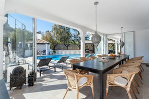 A modern outdoor dining area with wicker chairs, a pool, and a clear view of the surrounding neighborhood. - Holiday Home 'Beachfront Luxury Villa La Cala' with Private Pool, Wi-Fi and Air Conditioning (Las Lagunas de Mijas)