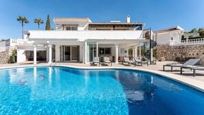 A modern villa with a swimming pool, outdoor seating, and a stone wall. - Holiday Home 'Beachfront Luxury Villa La Cala' with Private Pool, Wi-Fi and Air Conditioning (Las Lagunas de Mijas)