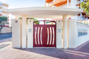 A gated entrance with a number '15' on the left, a red gate with white stripes, and a building with balconies and a window with a metal gate. - Apartment "Balcón Del Mar" with Shared Pool & Private Terrace (Canet d'en Berenguer)