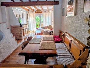 Een eethoek met een houten tafel, bankjes en uitzicht op de tuin.