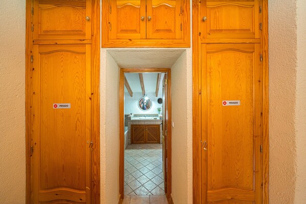 A hallway with wooden doors marked 'PRIVADO' leading to a bathroom with a sink and mirror. - Holiday Home "Can Lluna" (Tarbena)
