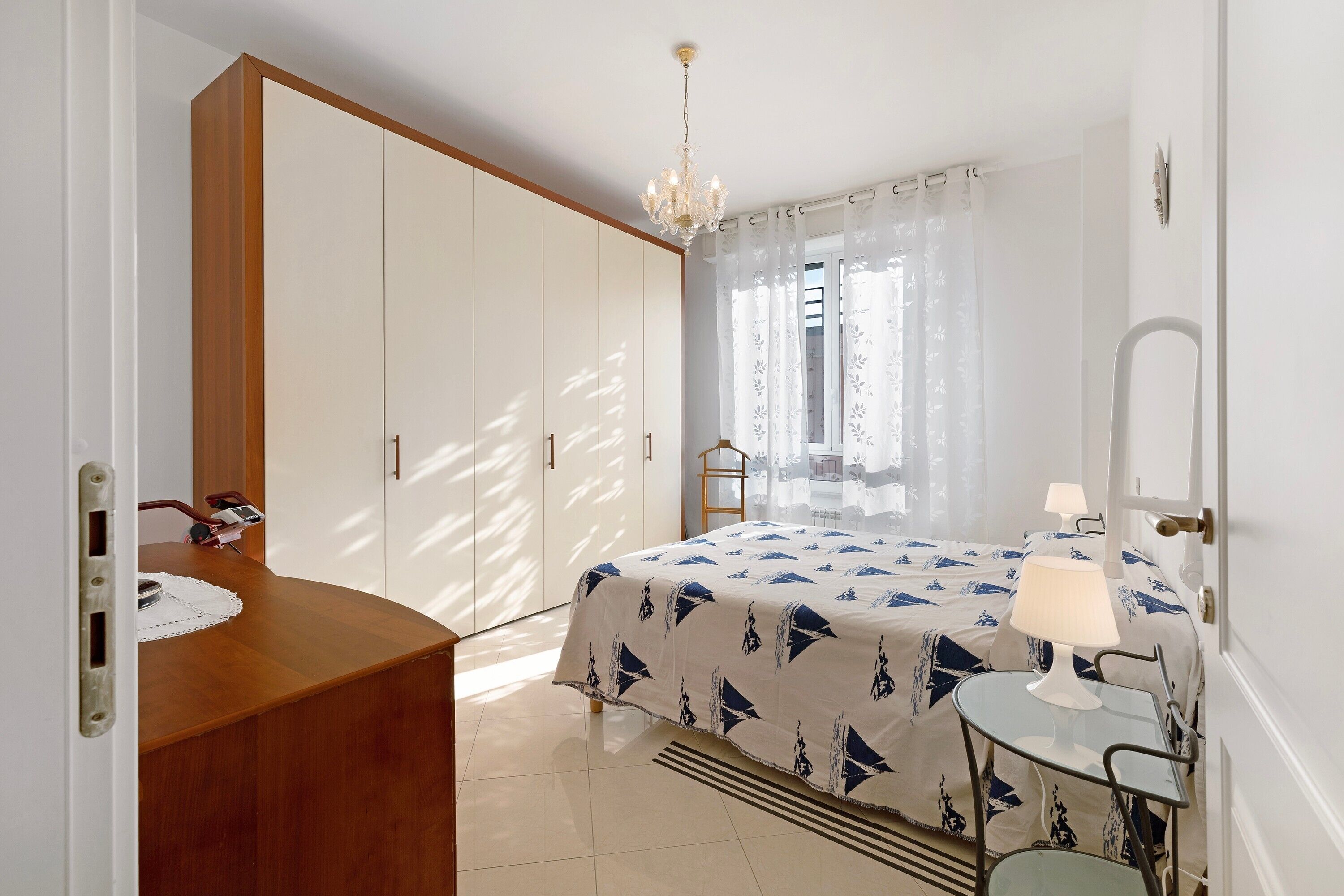 A bedroom with a bed, bedside table, lamp, and a wardrobe.