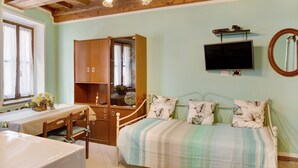 Een slaapkamer met een bed, een houten garderobe, een televisie en een raam met gordijnen.
