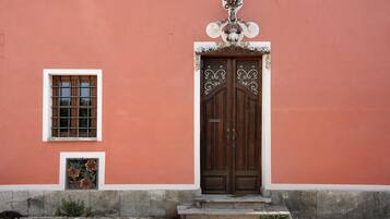 Un edificio con un'ampia porta in legno a due battenti, una piccola finestra a griglia e un cartello decorativo sopra la porta.