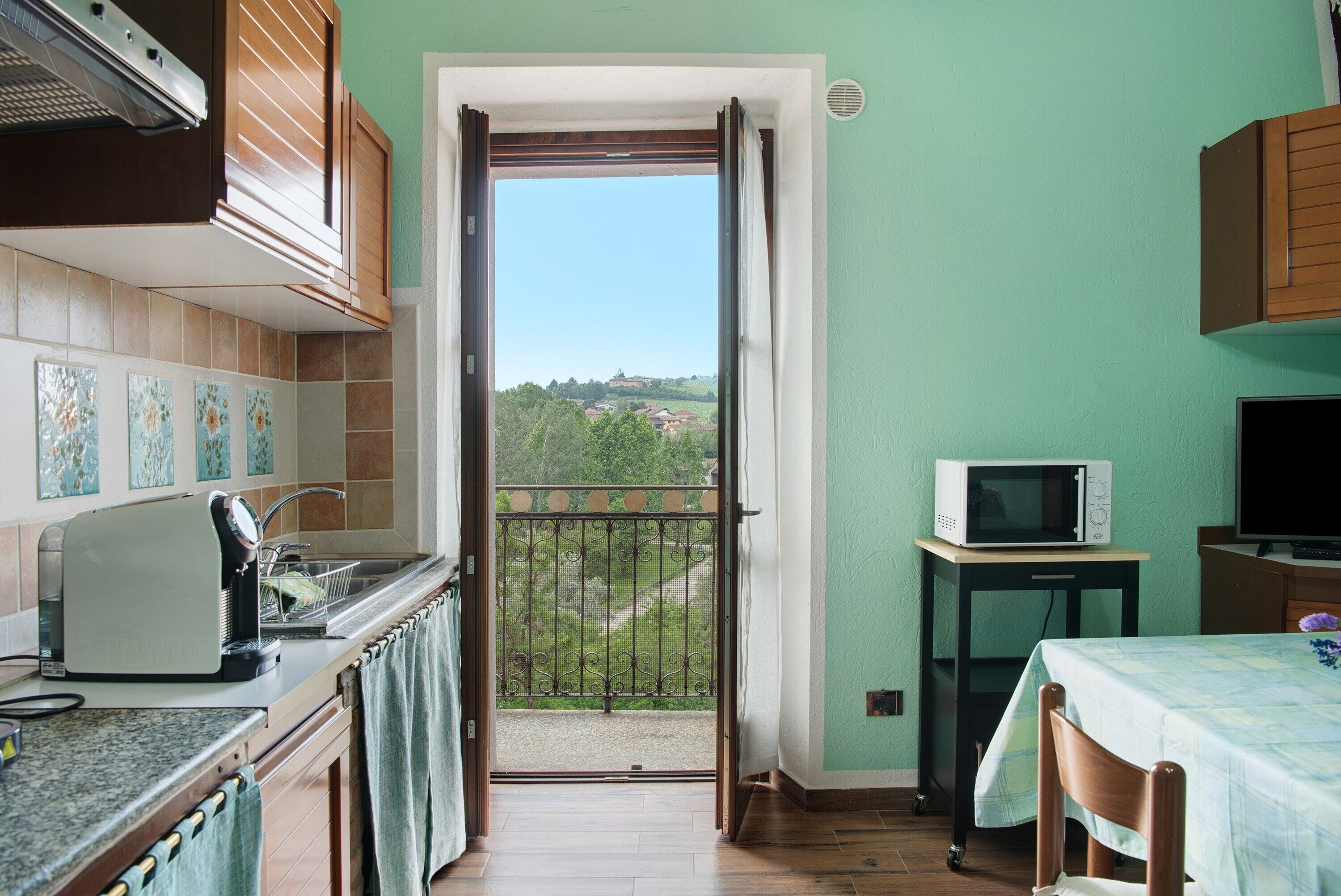Una cucina con vista su un balcone, un forno a microonde e un'area pranzo.