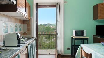 Una cucina con vista su un balcone, un forno a microonde e un'area pranzo.