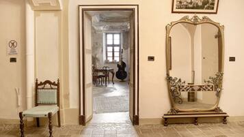 Un corridoio con una sedia, uno specchio e una porta che dà su un'altra stanza.