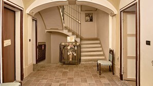 A staircase with a handrail, a console table with a vase, and a chair. - Apartment 'La Rocca di Efisio - Grignolino' with Balcony, Wi-Fi and Air Conditioning (Costigliole d'Asti)