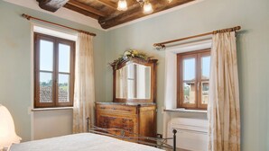 A bedroom with a bed, dresser, mirror, and two windows with curtains.