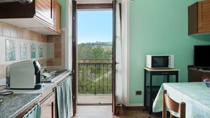 A kitchen with a view of a balcony, a microwave, and a dining area.