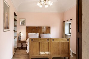 A bedroom with a wooden bed, a nightstand, a mirror, and a framed picture on the wall.