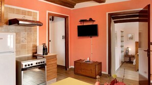 Una cucina con un fornello, un forno e una televisione montata a parete.