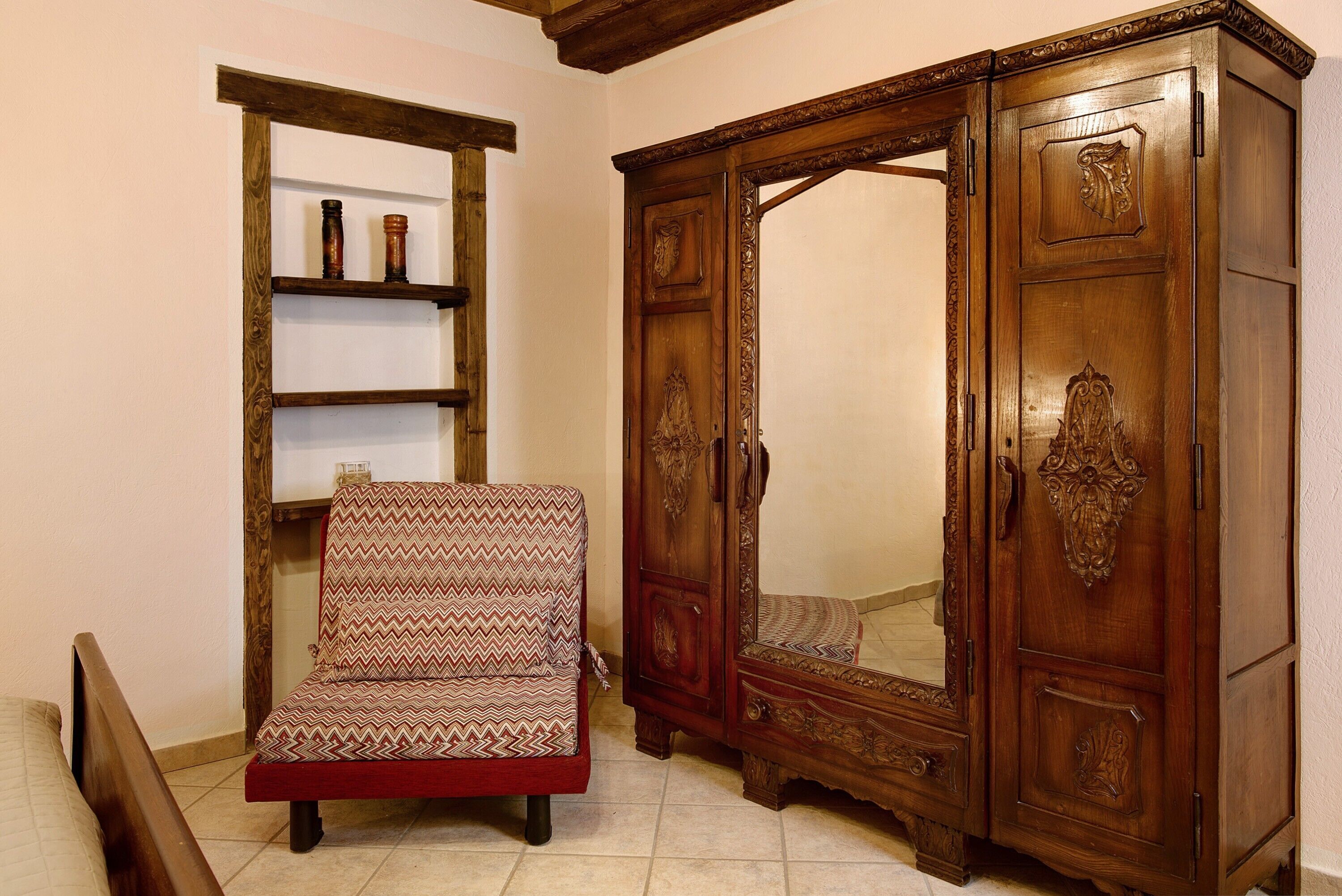 A room with a wooden chair, a wooden cabinet, and a shelf with decorative items.