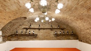 An arched brick room with a table and wine bottles on shelves. - Apartment 'La Rocca di Efisio - Barbera with Private Terrace, Wi-Fi and Air Conditioning (Costigliole d'Asti)
