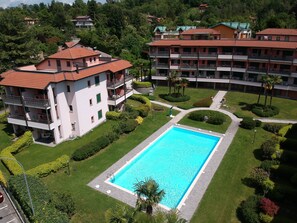 Un hotel con piscina, varios balcones y abundante vegetación.