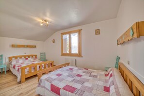 Un dormitorio con dos camas de madera, un ventanal y un radiador.