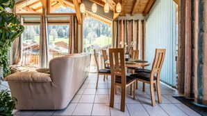 A wooden ceiling, a sofa, a dining table with chairs, and large windows. - Chalet for 4 in Morzine with Mountain View, Private Terrace, and Wi-Fi (Morzine)