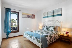 A bedroom with a bed, two bedside tables, a window with a view, and wall art.
