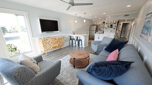 Ett modernt vardagsrum med en grå soffa, ett soffbord och en tv som är monterad på väggen.