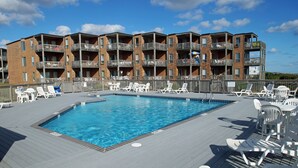 En swimmingpool med solstolar och en flervåningsbyggnad med balkonger.