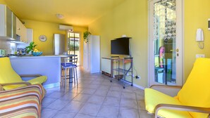 Ein kompakter Wohnraum mit einer Küche, einer Essecke und einem Balkon mit Glasdoor.