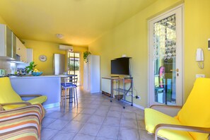 A compact living space with a kitchen, dining area, and a balcony with a glass door.