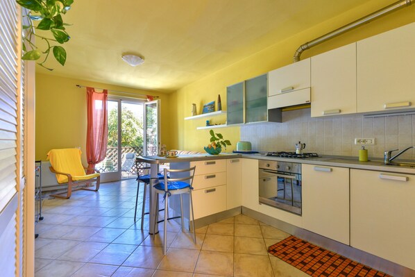 A kitchen with a dining area, a window with curtains, and a plant on the counter.